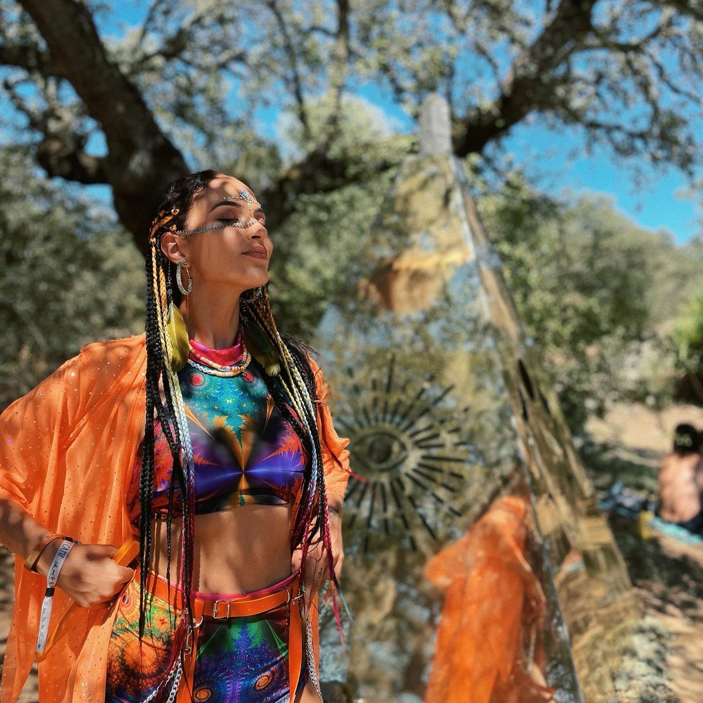 woman standing still in a boho style for rave festivals with crop top and high waisted booty shorts